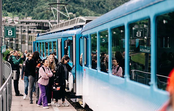 Touristen steigen in eine Bahn.